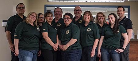The AUPE Occupational Health &amp; Safety Committee members stand together wearing matching dark green committee t-shirts.