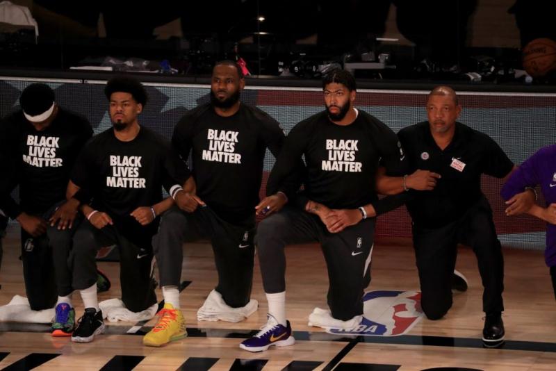 Professional basketball players, including Lebron James, kneel on the court while wearing matching shirts that read &quot;Black Lives Matter.&quot;