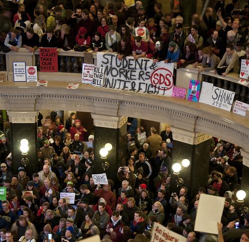 A large crowd of workers occupies the inside of the Wisconsin state capitol building