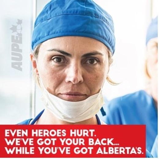 features a portrait photo of a healthcare worker wearing a mask pulled down. Text below the worker reads Even heroes hurt. We&#039;ve got your back...while you&#039;ve Alberta&#039;s
