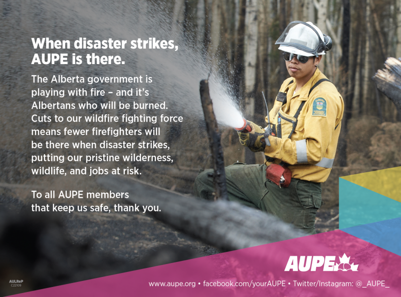 An AUPE member in firefighting gear wields a large water hose amidst a charred forest