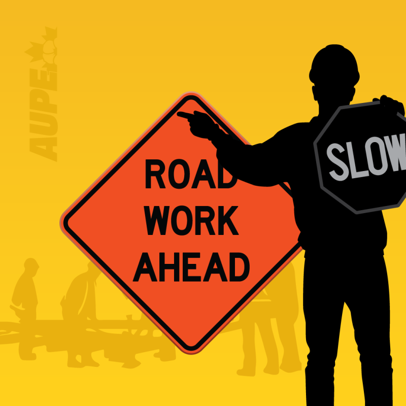 A road worker carries two signs which read "Slow" and "Road work ahead"