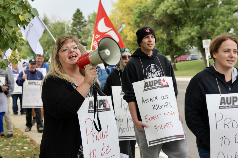 AUPE members walking a picket line, with one chanting into a megaphone.